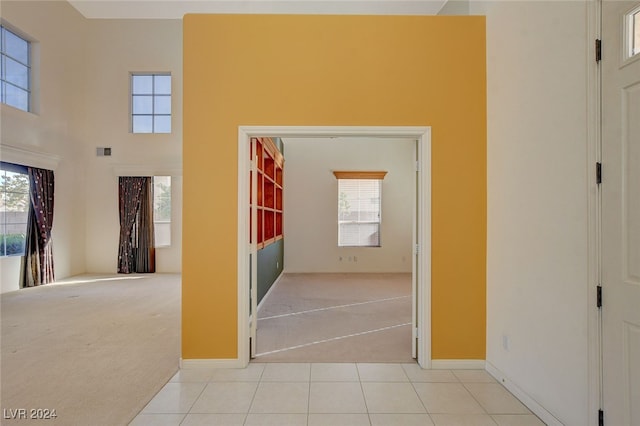 hall with light carpet and a towering ceiling