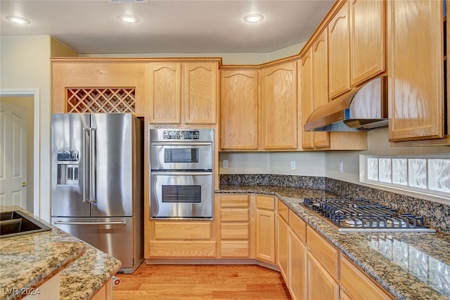 kitchen with sink, light hardwood / wood-style flooring, dark stone countertops, light brown cabinetry, and appliances with stainless steel finishes