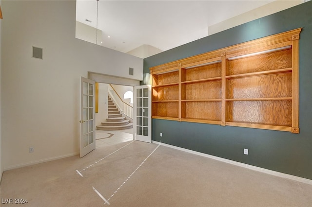 spare room featuring french doors and light colored carpet