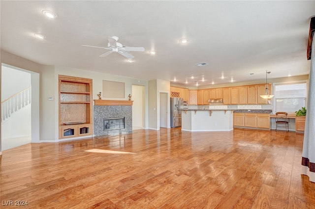 unfurnished living room featuring ceiling fan, a fireplace, and light hardwood / wood-style flooring