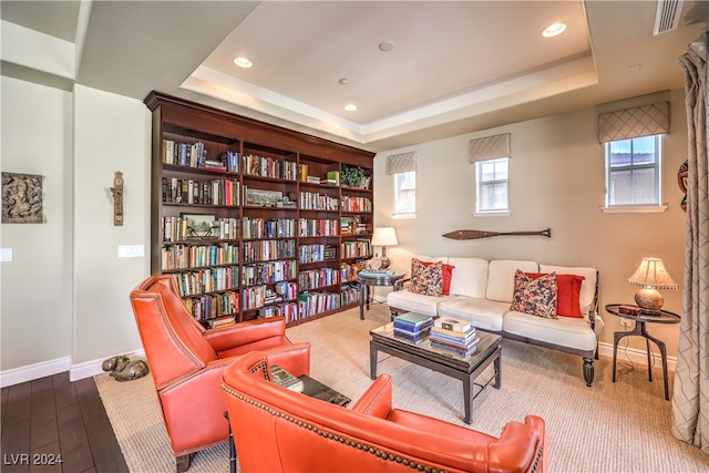 living area with a tray ceiling and wood-type flooring