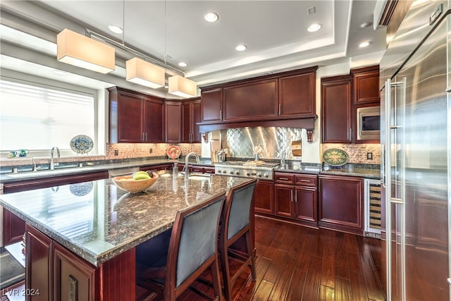 kitchen with wine cooler, a center island with sink, dark hardwood / wood-style flooring, appliances with stainless steel finishes, and dark stone countertops