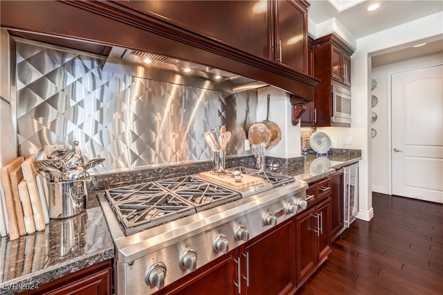 kitchen featuring appliances with stainless steel finishes, decorative backsplash, dark stone countertops, and dark wood-type flooring