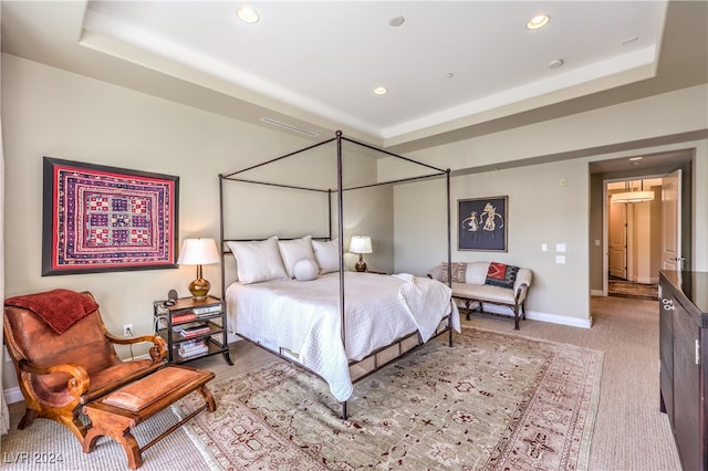 bedroom featuring light colored carpet and a tray ceiling