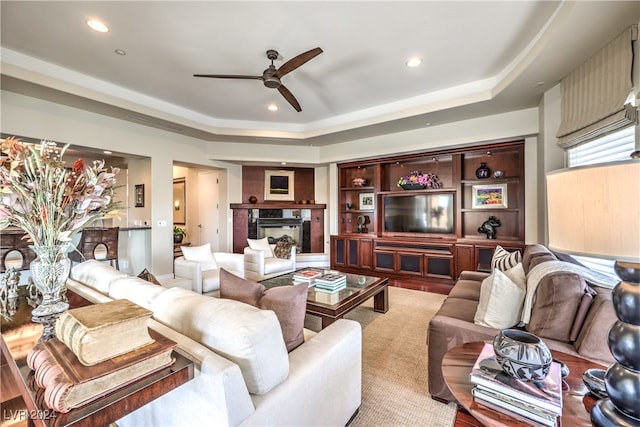 living room featuring ceiling fan, a raised ceiling, and a premium fireplace