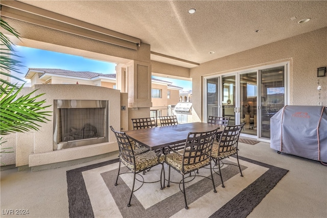 view of patio featuring an outdoor fireplace and a grill