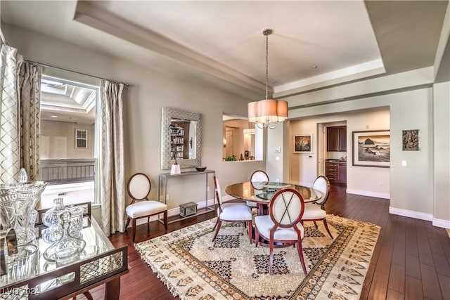 dining area featuring a notable chandelier, a raised ceiling, and dark hardwood / wood-style flooring