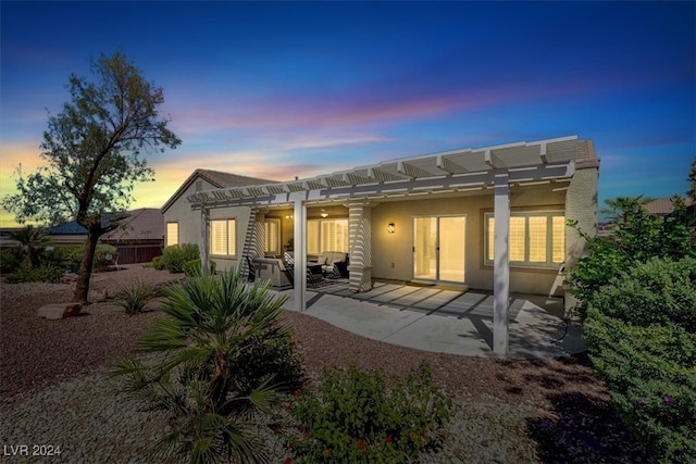 back house at dusk featuring a patio area and a pergola