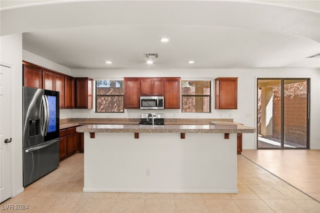 kitchen featuring light hardwood / wood-style floors, a kitchen island with sink, a breakfast bar area, and stainless steel appliances