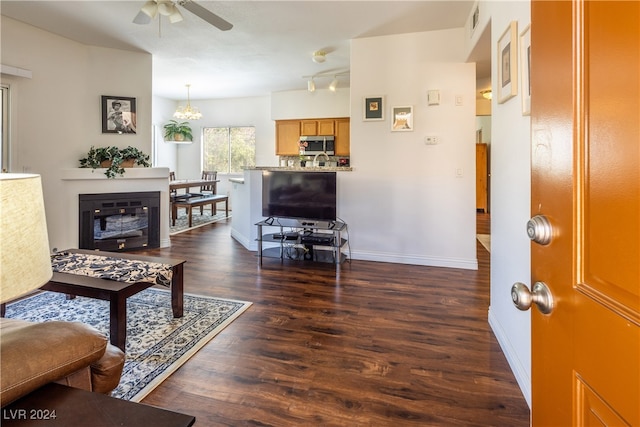 living room with dark wood-type flooring and ceiling fan with notable chandelier