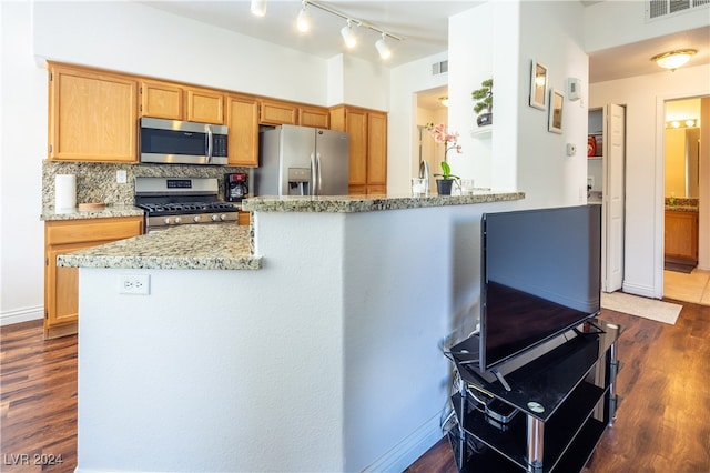 kitchen featuring appliances with stainless steel finishes, dark hardwood / wood-style floors, backsplash, kitchen peninsula, and light stone countertops