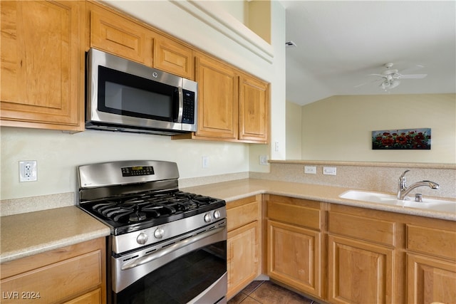 kitchen featuring sink, vaulted ceiling, stainless steel appliances, tile patterned floors, and ceiling fan