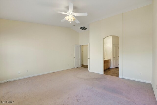 unfurnished bedroom with ceiling fan, light colored carpet, connected bathroom, and vaulted ceiling