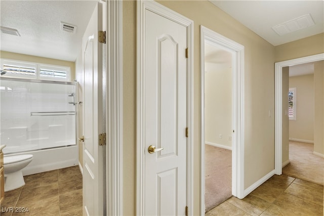 hall with a textured ceiling and light colored carpet