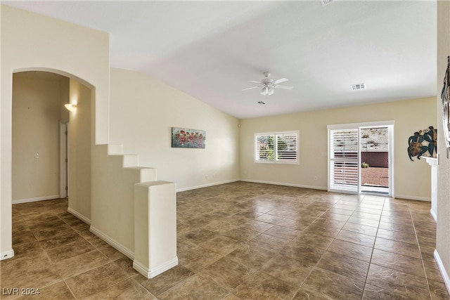 unfurnished living room with vaulted ceiling, ceiling fan, and dark tile patterned flooring