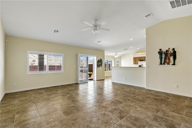 empty room with ceiling fan, vaulted ceiling, and tile patterned floors