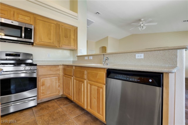 kitchen featuring dark tile patterned floors, sink, lofted ceiling, appliances with stainless steel finishes, and ceiling fan