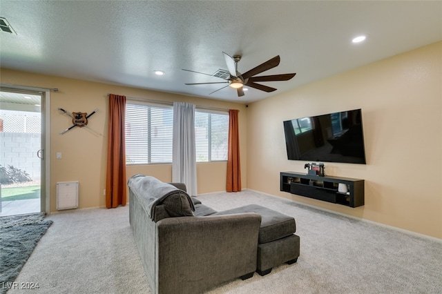 living room with light carpet, ceiling fan, and a textured ceiling