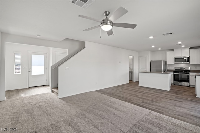 interior space featuring appliances with stainless steel finishes, white cabinets, a center island, ceiling fan, and hardwood / wood-style flooring