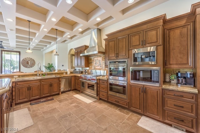 kitchen with pendant lighting, coffered ceiling, wall chimney exhaust hood, beamed ceiling, and stainless steel appliances