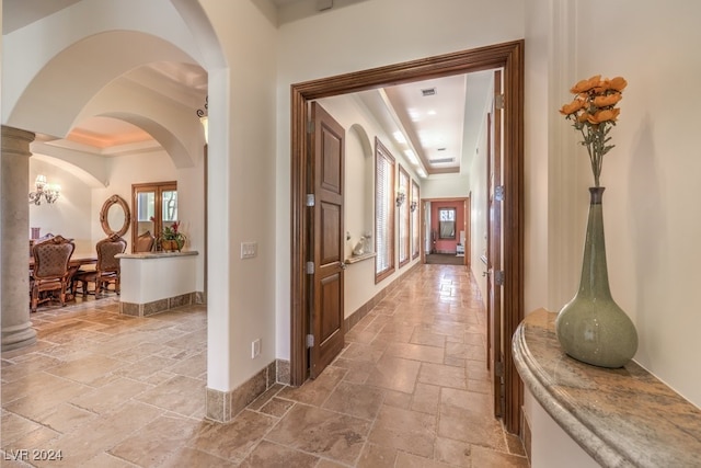 corridor featuring a tray ceiling and ornamental molding