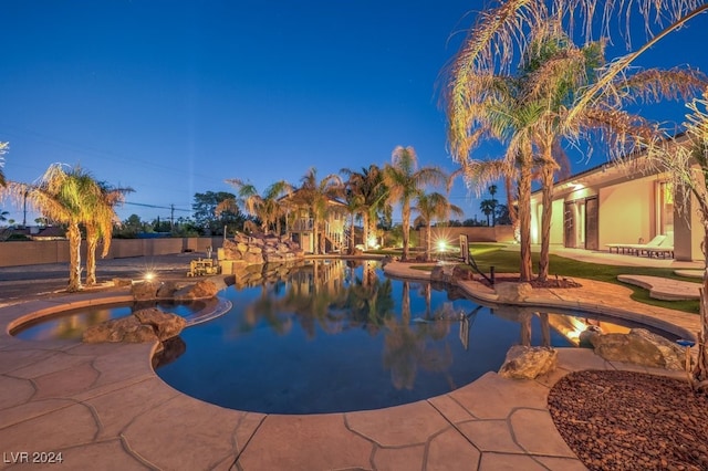 pool at dusk with a patio area and an in ground hot tub