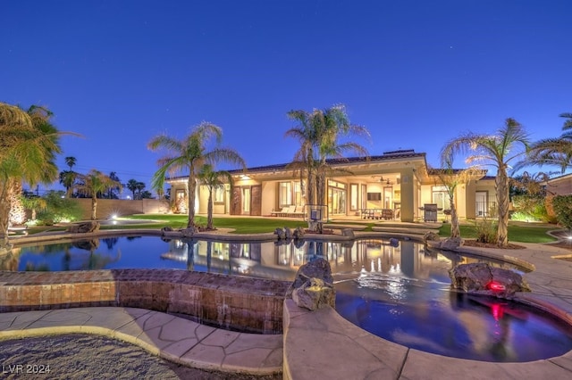 pool at dusk featuring an in ground hot tub and a patio