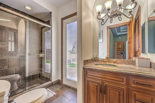 bathroom featuring vanity, an inviting chandelier, a shower with shower door, and toilet