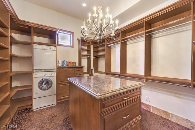 spacious closet with stacked washer / drying machine, dark carpet, and a chandelier