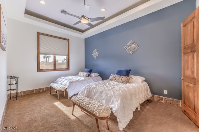 bedroom featuring light carpet, a raised ceiling, and ceiling fan