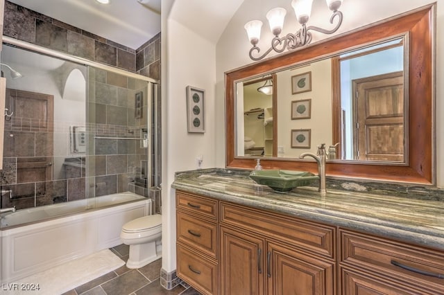 full bathroom with vanity, bath / shower combo with glass door, vaulted ceiling, tile patterned flooring, and toilet