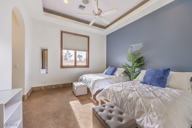 carpeted bedroom featuring a raised ceiling and ceiling fan