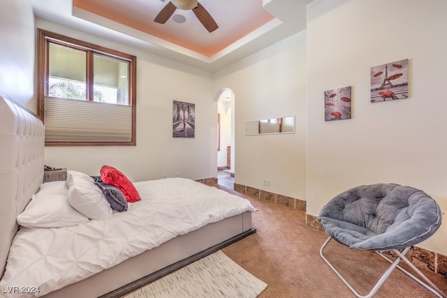 carpeted bedroom featuring ceiling fan and a raised ceiling