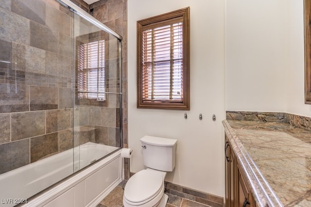 full bathroom with vanity, bath / shower combo with glass door, and toilet