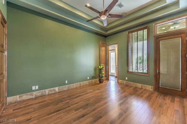 spare room with hardwood / wood-style flooring, ceiling fan, and a raised ceiling