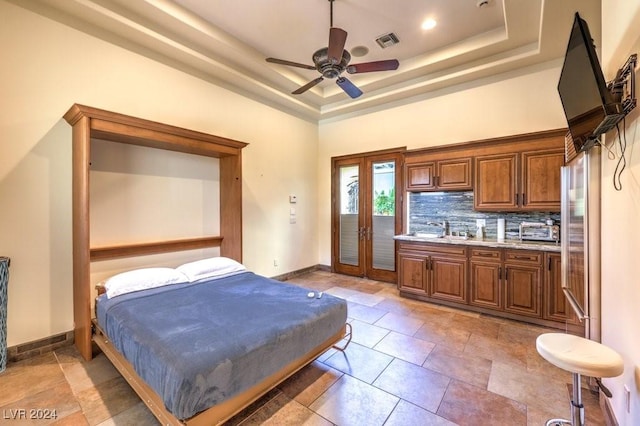 bedroom with stainless steel refrigerator, ceiling fan, french doors, sink, and a tray ceiling