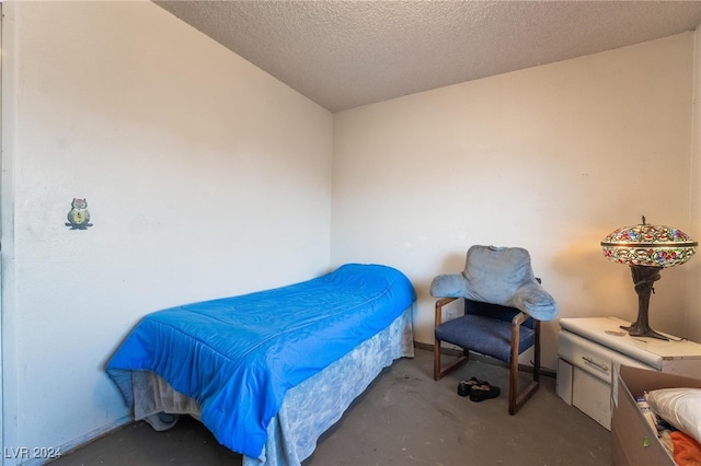 bedroom with a textured ceiling and concrete floors