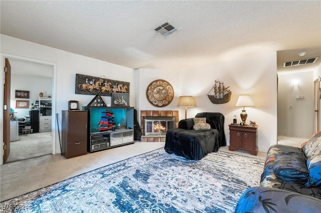 living room with a textured ceiling and a tiled fireplace