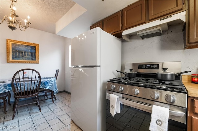 kitchen featuring light tile patterned flooring, a textured ceiling, stainless steel gas stove, an inviting chandelier, and white fridge