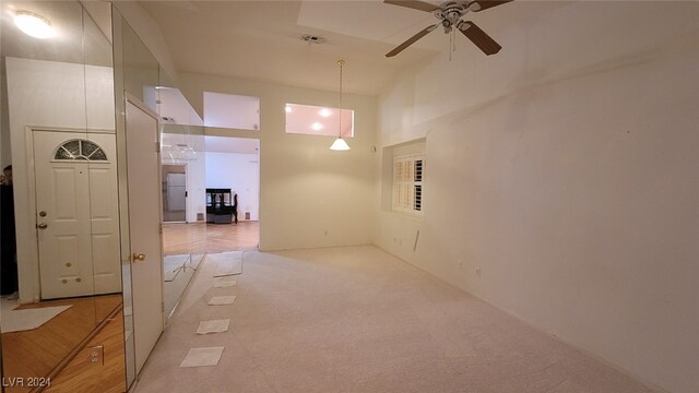 carpeted spare room with ceiling fan and high vaulted ceiling