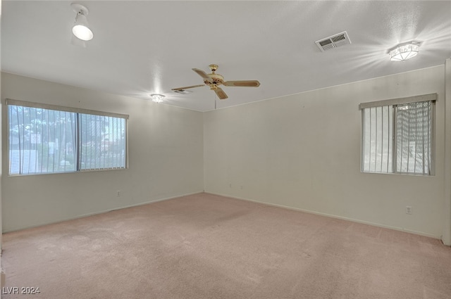 carpeted spare room with ceiling fan and plenty of natural light