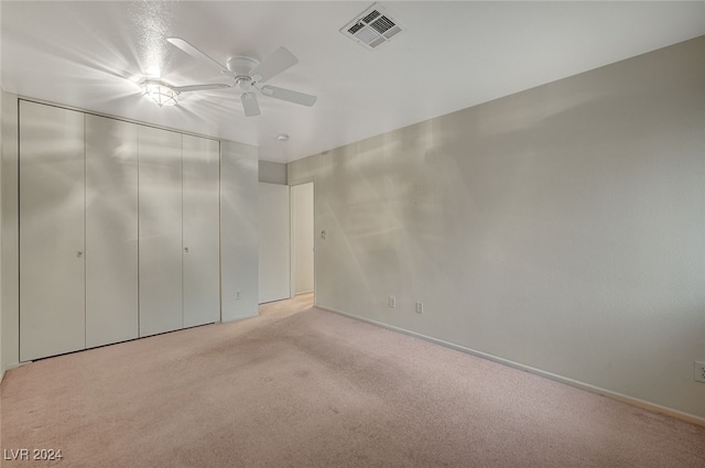 unfurnished bedroom featuring ceiling fan, a closet, and light carpet