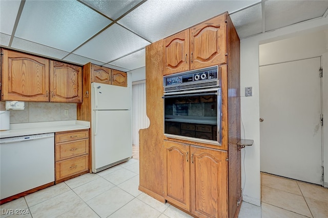 kitchen featuring a drop ceiling, decorative backsplash, white appliances, and light tile patterned floors