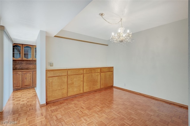 spare room with a notable chandelier and light parquet flooring