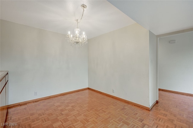 empty room featuring light parquet floors and a chandelier