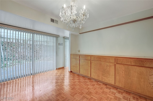 spare room with a notable chandelier and light parquet floors