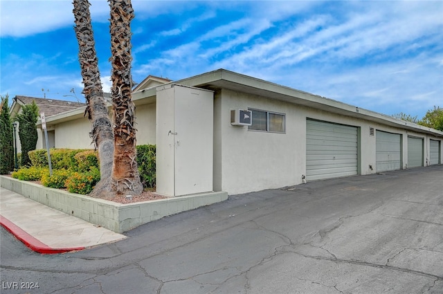 view of front of home featuring a garage and a wall mounted AC