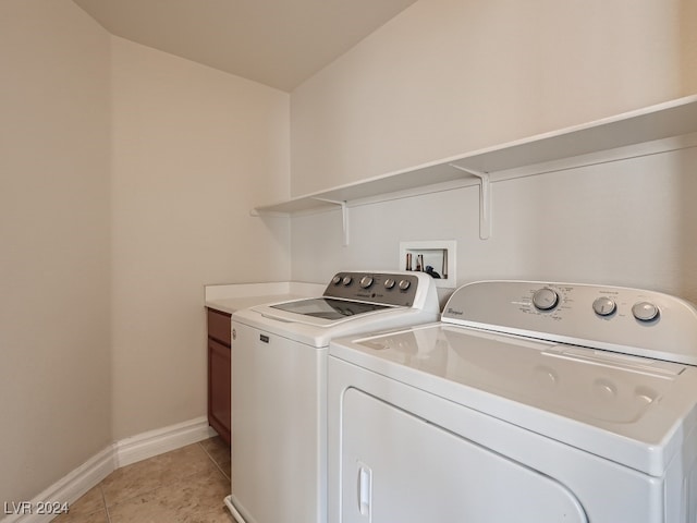 clothes washing area featuring separate washer and dryer, light tile patterned floors, and cabinets