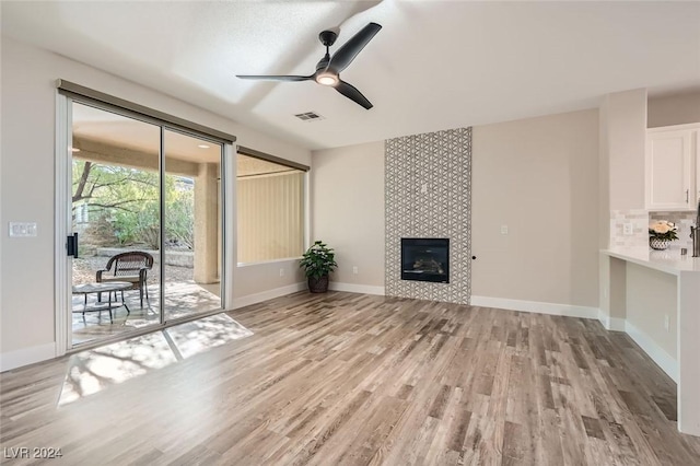 unfurnished living room featuring a fireplace, light hardwood / wood-style floors, and ceiling fan