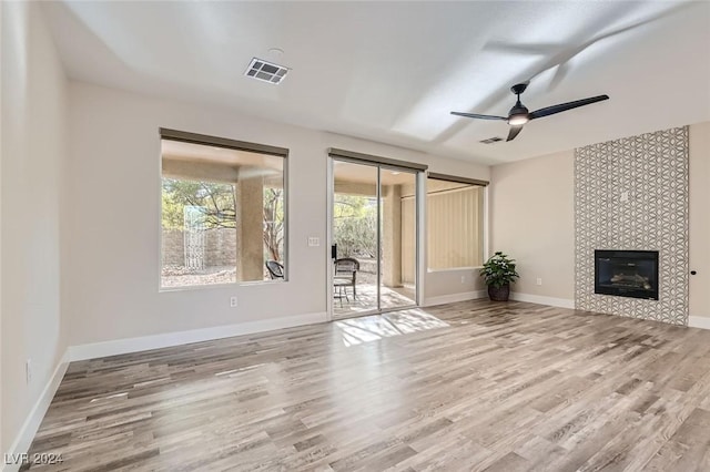 unfurnished living room featuring hardwood / wood-style floors, a tile fireplace, and ceiling fan